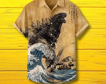 May include: Tan button-up shirt featuring a Godzilla graphic in a Japanese art style. The design includes a large wave, a mountain, and Japanese text. The shirt has short sleeves and a classic collar.