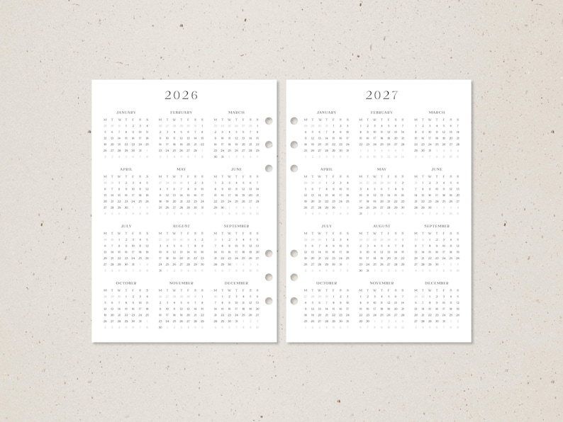 K&ouml;nnte beinhalten: Zwei wei&szlig;e Planerseiten mit Kalendern f&uuml;r die Jahre 2026 und 2027. Jede Seite hat ein Kalenderraster mit Monaten und Tagen. Die Seiten sind mit L&ouml;chern zum Binden vorgestanzt.