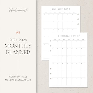May include: An A5 2027-2028 monthly planner with white pages featuring black text and grid lines. The planner includes monthly calendar layouts for January and February 2027, with punch holes on the side for binding. Text reads PaperSeasonsCo.