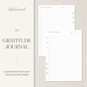 Peut inclure: Un journal de gratitude A5 avec des pages lignées pour les entrées quotidiennes. La couverture présente le texte "GRATITUDE JOURNAL" et "CULTIVATE POSITIVITY DAILY ONE LINE A DAY FORMAT". Le journal est blanc avec un design minimaliste.
