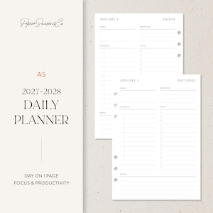 May include: A5 2027-2028 daily planner refill pages with a day-on-one-page layout. The white paper features sections for goals, priorities, schedule, to-do lists, and notes, with punched holes for binder rings. Text includes PaperSeasonsCo.