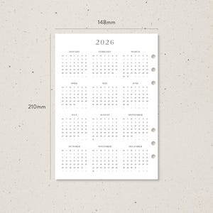 K&ouml;nnte beinhalten: A5-Kalenderseite f&uuml;r 2026 mit minimalistischem Design. Der Kalender ist in Grau auf wei&szlig;em Papier gedruckt, mit einer Anordnung der Monate oben und der Tage in Reihen. Die Seite misst 14,8 cm x 21 cm.