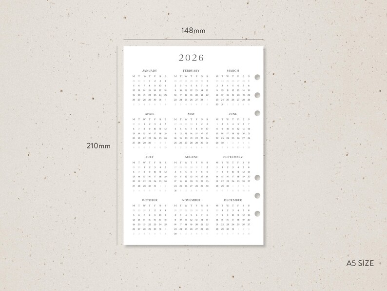 K&ouml;nnte beinhalten: A5-Kalenderseite f&uuml;r 2026 mit minimalistischem Design. Der Kalender ist in Grau auf wei&szlig;em Papier gedruckt, mit einer Anordnung der Monate oben und der Tage in Reihen. Die Seite misst 14,8 cm x 21 cm.