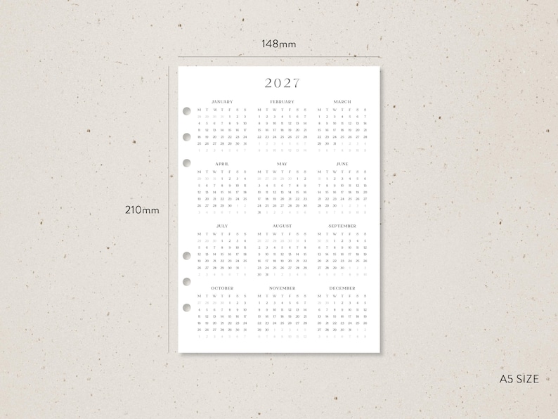 K&ouml;nnte beinhalten: A5-Kalendereinlage f&uuml;r 2027, misst 14,8 cm x 21 cm, mit minimalistischem Design. Der Kalender hat ein einfaches Layout mit dem Jahr oben und den Monaten darunter. Das Papier ist f&uuml;r einen Ordner vorgestanzt.