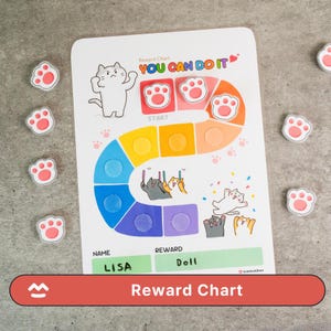 Könnte beinhalten: Eine weiße Belohnungstafel mit einem farbenfrohen Pfad, Katzenillustrationen und dem Text "YOU CAN DO IT." Die Tafel enthält Felder für einen Namen und eine Belohnung, wobei "LISA" und "DOLL" ausgefüllt sind. Pfotenförmige Aufkleber umgeben die Tafel.