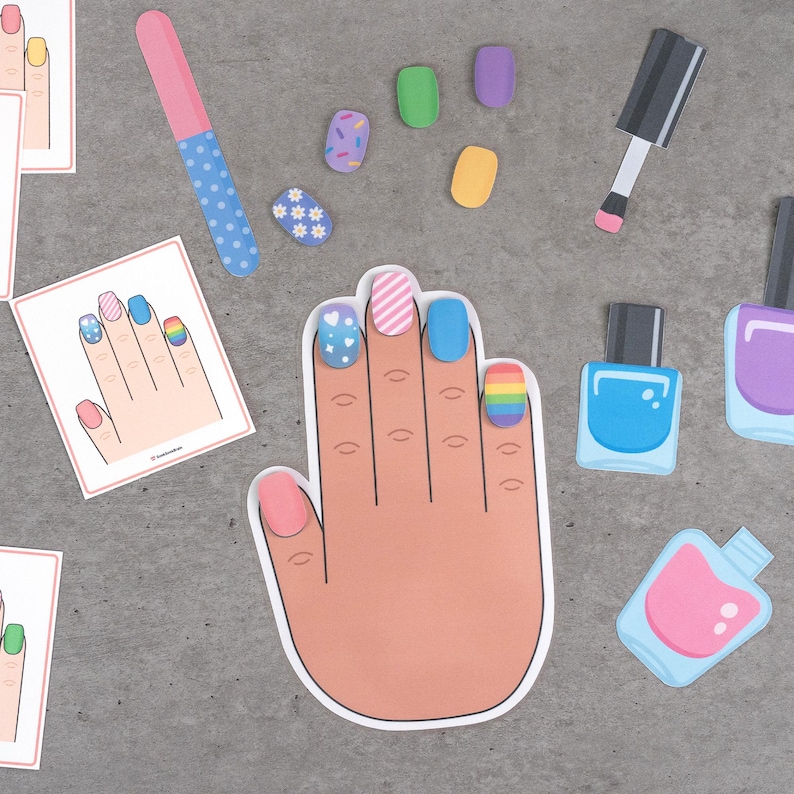 May include: A collection of nail art-themed cutouts, including a hand with painted nails, nail polish bottles, a nail file, and individual nail designs. The nails are painted with various designs, including stripes, hearts, and rainbows.