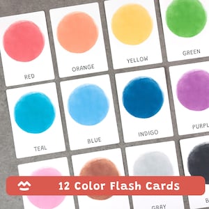 Pode incluir: Um conjunto de 12 cartões de cores. Cada cartão apresenta um círculo em aquarela em uma cor diferente, com o nome da cor impresso abaixo. As cores incluem vermelho, laranja, amarelo, verde, verde-azulado, azul, índigo, roxo, marrom, cinza, preto e rosa.