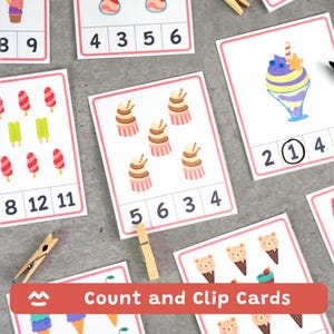 Puede incluir: Un conjunto de tarjetas educativas de contar y sujetar con ilustraciones de cupcakes, conos de helado y dulces con forma de oso. Cada tarjeta tiene un borde rosa, un grupo de elementos para contar y una fila de números con la respuesta rodeada.
