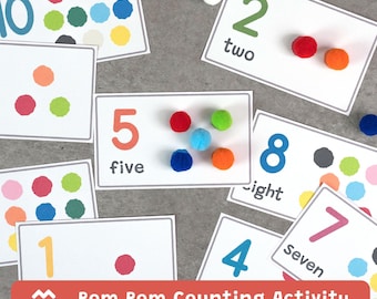 May include: Educational counting activity set featuring cards with numbers 1-10, written words, and colorful pom-poms. The cards have a white background with a gray border. The text "Pom Pom Counting Activity" is at the bottom.