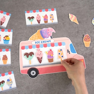 May include: A pink ice cream truck cutout featuring the text ICE CREAM, decorated with various colorful paper ice cream and popsicle shapes. The truck display includes a heart-shaped treat, a bunny-themed cone, a sundae, and a fruit popsicle.
