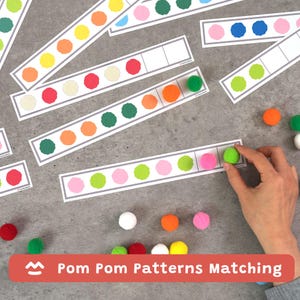 Pode incluir: Jogo educativo com cartões e pompons. Os cartões apresentam círculos coloridos e espaços para combinar pompons. Os pompons são de várias cores, incluindo rosa, verde, laranja e azul. O texto "Pom Pom Patterns Matching" é exibido em uma faixa vermelha.