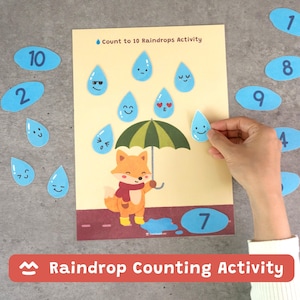Puede incluir: Una hoja de actividad Count to 10 Raindrops con un zorro de dibujos animados sosteniendo un paraguas verde. La página incluye gotas de lluvia azules con expresiones faciales, un suelo rojo oscuro y fichas ovaladas azules numeradas del 1 al 10.
