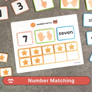 May include: A white Number Matching game board with the number 7, the word "seven", and star-shaped tiles. The board also features illustrations of hands and a lion and bear graphic. The game includes number cards.