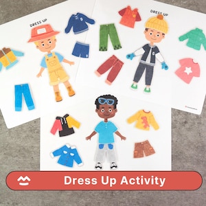 Puede incluir: Un juego de actividades de disfraces para niños con muñecos de papel ilustrados y recortes de ropa. El juego incluye tres muñecos de papel con varios atuendos, incluyendo camisas, pantalones, pantalones cortos y chaquetas. El texto "Dress Up Activity" se muestra en una pancarta roja.
