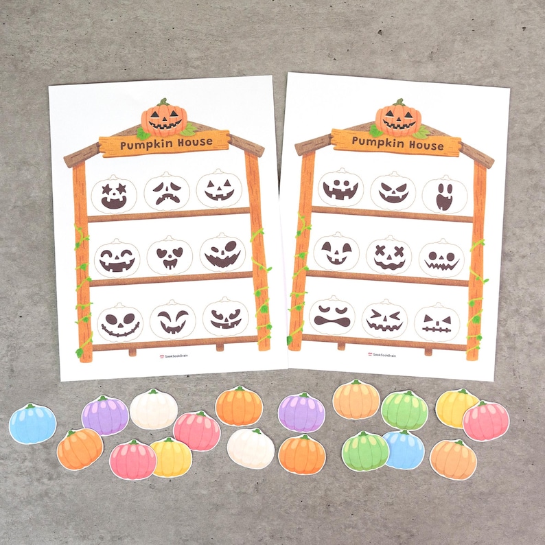May include: Two white paper sheets featuring a wooden shelf illustration labeled Pumpkin House, each with nine empty pumpkin outlines. Below the sheets are twenty-two small, colorful, die-cut pumpkin shapes in shades of orange, pink, yellow, green, blue, purple, and white.