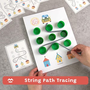May include: A white sheet with green bottle caps and a gray string path. The sheet has a car graphic and the words "LET'S GO!". Additional cards with car and house graphics are visible. The text "String Path Tracing" is at the bottom.