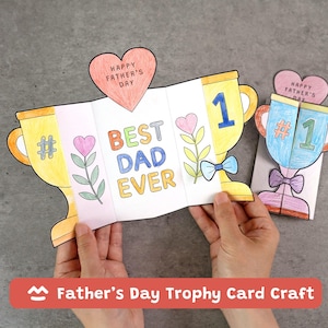 May include: A handmade Father's Day trophy card with the words "BEST DAD EVER" in colourful letters. The card is shaped like a trophy and includes a heart-shaped topper that says "HAPPY FATHER'S DAY". The card is yellow, blue, and pink.