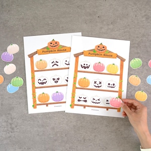 May include: Two identical white paper sheets titled Pumpkin House, featuring a brown wooden shelf illustration with three levels. Each shelf displays various colorful pumpkin cutouts with different facial expressions, including orange, pink, yellow, and purple.