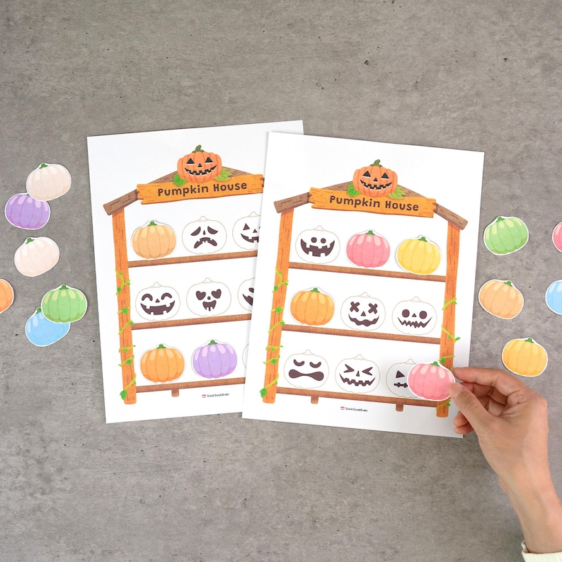 May include: Two identical white paper sheets titled Pumpkin House, featuring a brown wooden shelf illustration with three levels. Each shelf displays various colorful pumpkin cutouts with different facial expressions, including orange, pink, yellow, and purple.