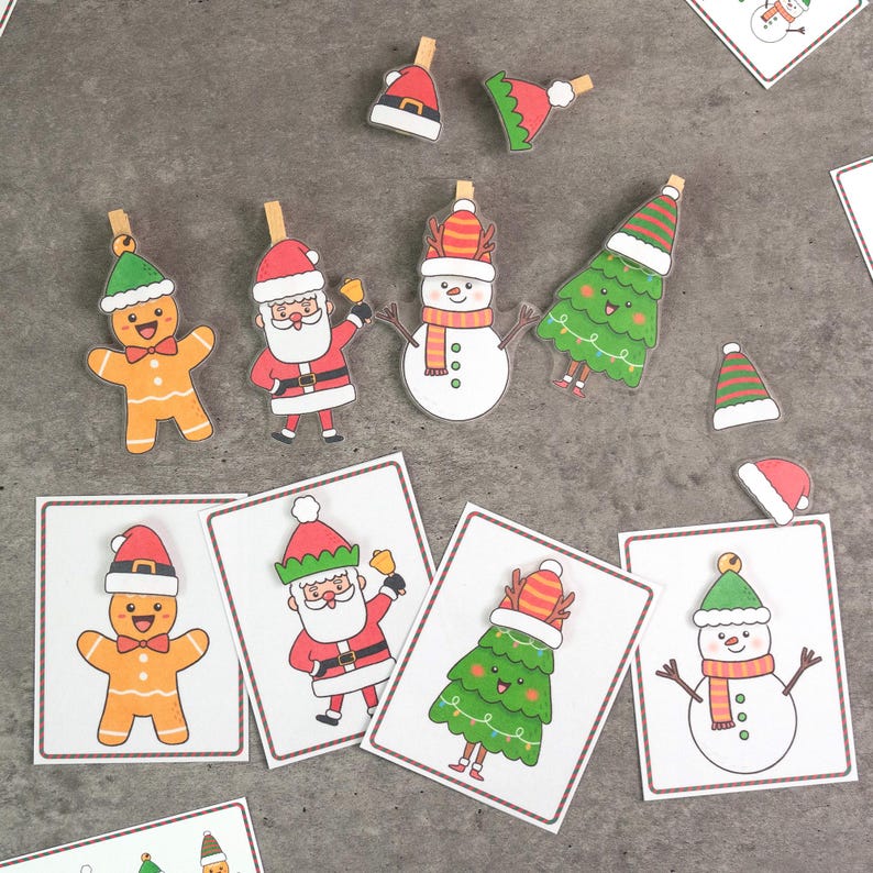 Puede incluir: Un conjunto de clips y tarjetas con tem&aacute;tica navide&ntilde;a. Los clips presentan hombres de jengibre, Pap&aacute; Noel, mu&ntilde;ecos de nieve y &aacute;rboles de Navidad. Las tarjetas tienen dise&ntilde;os similares con acentos rojos y verdes, ideales para manualidades navide&ntilde;as.