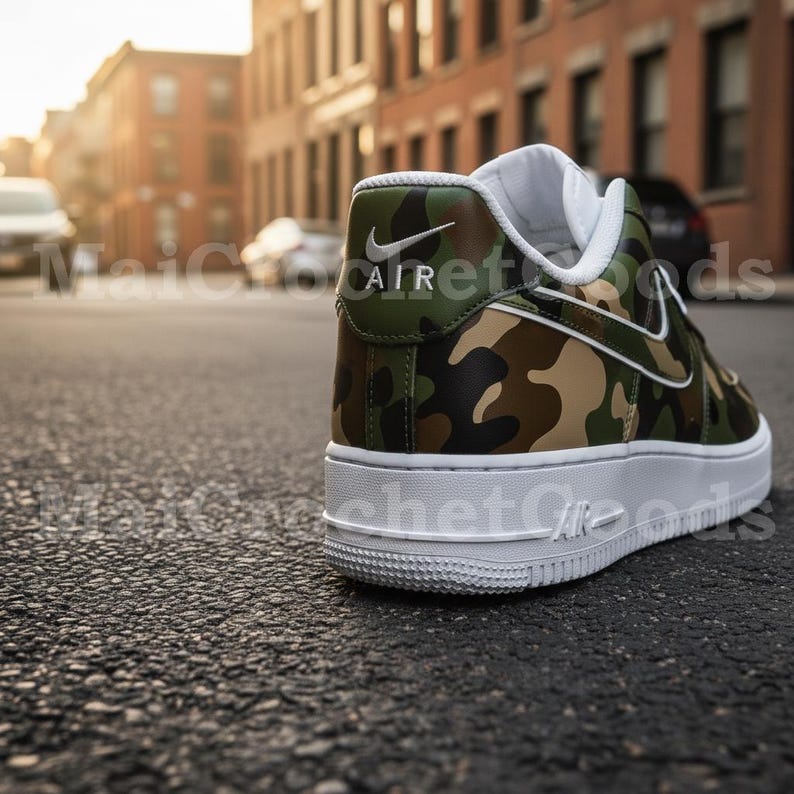 May include: A close-up of a camouflage-patterned sneaker with a white sole. The shoe features a green, brown, and tan camouflage design with a white Nike swoosh. The word "AIR" is visible on the heel.