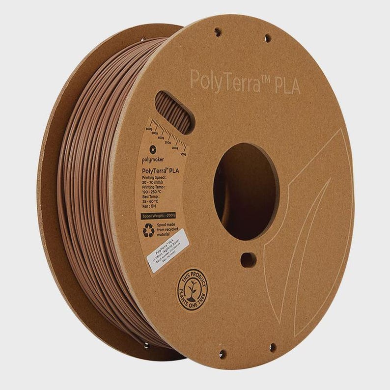 May include: A spool of PolyTerra PLA 3D printing filament in a warm brown color. The spool is made from recycled materials and has printed information on the side. The text "PolyTerra PLA" is visible on the cardboard spool.