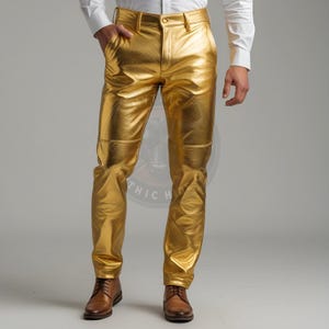 Puede incluir: Pantalones dorados metálicos con un diseño clásico de cinco bolsillos. Los pantalones tienen una superficie brillante y reflectante y un corte recto. Los pantalones se combinan con zapatos de cuero marrón y una camisa blanca abotonada.