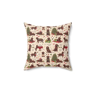 May include: A square throw pillow with a cream background featuring a repeating pattern of brown Labrador dogs in various Christmas scenes, including decorated trees, presents, stockings, and text like Dear Santa I can explain and Good Dogs Maybe.
