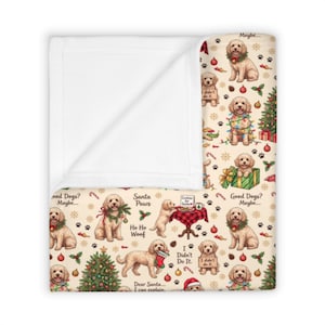 Könnte beinhalten: Eine cremefarbene Decke mit einem weihnachtlichen Muster aus Golden Doodle Hunden, geschmückten Tannenbäumen, roten Weihnachtskugeln, Zuckerstangen und Pfotenabdrücken. Der Text enthält "Good Dogs? Maybe...", "Santa Paws" und "Ho Ho Woof".
