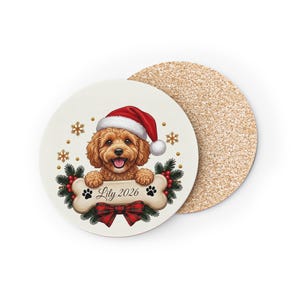 Könnte beinhalten: Ein runder Untersetzer mit Korkrückseite zeigt einen braunen, lockigen Hund mit roter Weihnachtsmütze. Der Hund liegt auf einem knochenförmigen Schild mit der Aufschrift Lily 2026, umgeben von grünen Tannenzweigen, roten Beeren und goldenen Schneeflocken.