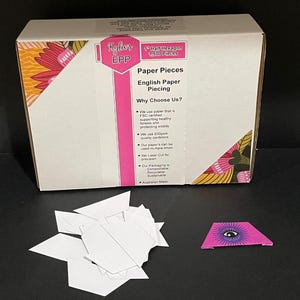 May include: A box of 1,500 1-inch half hexagon paper pieces for English paper piecing. The box is white with pink and yellow floral designs. The text on the box reads "Kylter EPP Paper Pieces English Paper Piecing Why Choose Us? We use paper that is FSC certified supporting healthy forests and protecting wildlife We use 200gsm quality cardstock Our paper's can be used multiple timers We Laser Cut for precision Our Packaging is Compostable Recyclable Sustainable Australian Made".