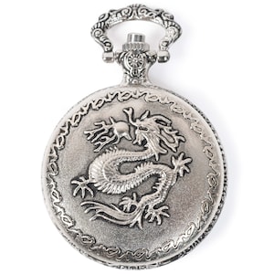May include: Silver pocket watch with a detailed dragon design on the face. The watch has a decorative ornate top.