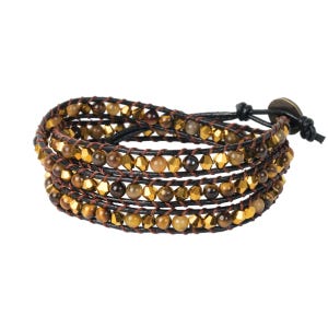 May include: Wrap bracelet featuring multiple strands of brown and gold beads, interspersed with metallic gold accents. The bracelet is secured with a leather strap and a button clasp. The design is suitable for everyday wear.
