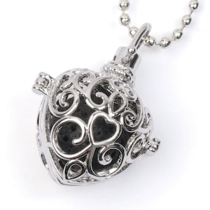 May include: Silver heart-shaped aromatherapy diffuser necklace with a delicate filigree design. The diffuser is filled with black lava rock beads.