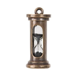 May include: A small antique brass hourglass pendant with a clear glass bulb and black sand. The hourglass is about 2 inches tall.