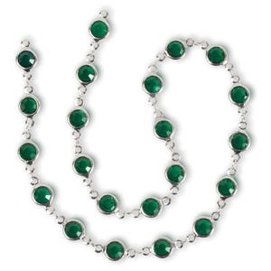 May include: A silver necklace featuring round, emerald-green gemstones. The gemstones are set in individual bezels and connected by delicate silver links. The necklace is displayed against a white background, highlighting the vibrant green of the stones.