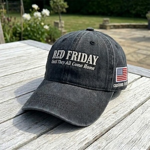 May include: A charcoal grey baseball cap with a distressed finish featuring the embroidered white text RED FRIDAY Until They All Come Home on the front and a small rectangular American flag patch on the side with the text custom text below it.