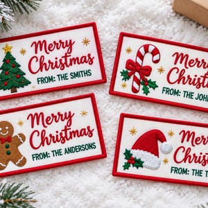 May include: Four rectangular embroidered gift tags with white fabric and red borders. Each tag features the red text Merry Christmas, a green From: family name, and a unique icon: a Christmas tree, candy cane, gingerbread man, or Santa hat.
