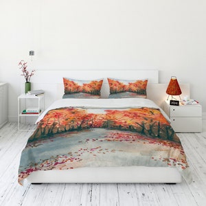 May include: A white duvet cover with a watercolor painting of an autumn forest scene. The painting features orange, red, and yellow leaves on trees with a gray path in the foreground.