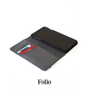 A black smartphone is placed inside a gray wallet, which is lying on a white surface.