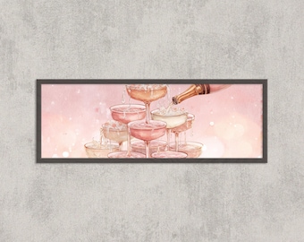May include: A framed print shows a champagne tower with champagne being poured from a bottle. The champagne glasses are arranged in a pyramid, with champagne cascading down. The background is a soft pink with bokeh effects.