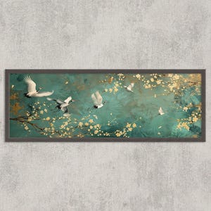 May include: A framed artwork with a teal backdrop, depicting white cranes in flight. Gold floral details and branches are spread across the scene. The artwork is enclosed in a dark grey frame, offering a tranquil and refined appearance.