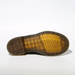May include: A close-up of the sole of a black boot, showcasing the distinctive yellow and brown tread pattern. The sole is made of a durable material, with a grid-like design for grip. The boot's design is visible, with a focus on the sole's construction.