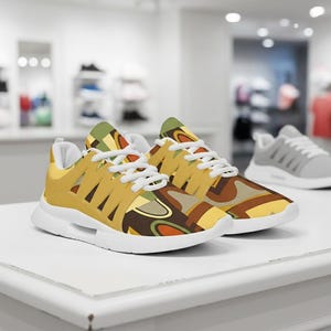 Puede incluir: Un par de zapatillas deportivas de estilo retro con un estampado vibrante en tonos amarillos, marrones, verdes y naranjas. Las zapatillas tienen cordones y suelas blancas. El diseño presenta una mezcla de formas geométricas y líneas curvas.