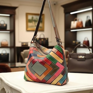 Könnte beinhalten: Eine bunte Patchwork-Leder-Umhängetasche mit geometrischem Design. Die Tasche hat eine Vielzahl von Farben, darunter Rot, Grün, Blau und Orange. Sie hat einen langen Riemen und steht auf einer weißen Oberfläche.