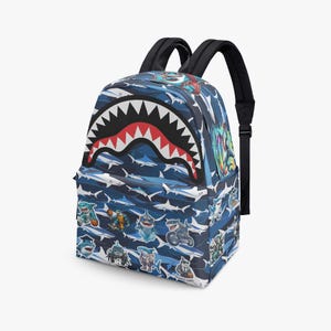 May include: Blue backpack with a shark mouth design on the front. The backpack features a pattern of white and blue sharks, with various cartoon shark stickers. It has black shoulder straps and a top handle.