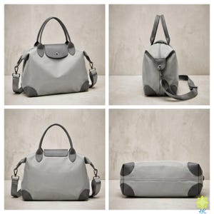 Puede incluir: Una bolsa de viaje gris claro con una correa para el hombro a juego y detalles en gris oscuro en las esquinas, el asa y la solapa. La bolsa tiene forma rectangular con un asa superior y una correa para el hombro desmontable. La bolsa est&aacute; hecha de un material duradero.