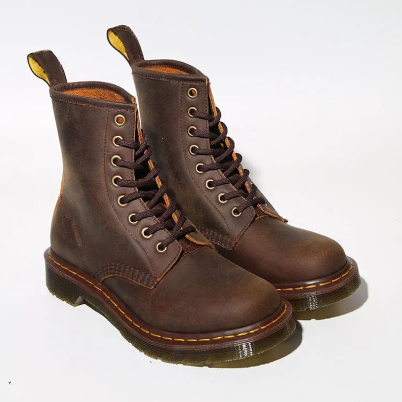May include: A pair of brown leather boots with a lace-up design. The boots have a classic style with a rounded toe, a sturdy sole, and a pull tab at the back. The boots are approximately 8 inches tall.