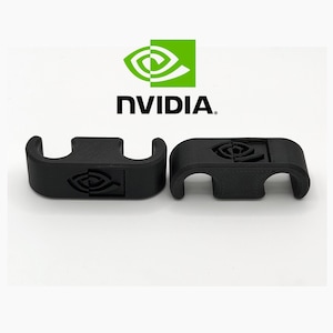 Puede incluir: Dos soportes negros impresos en 3D con el logotipo de NVIDIA. Los soportes tienen un diseño curvo con una ranura para sujetar algo. El logotipo de NVIDIA también está impreso en los soportes. El fondo es blanco.