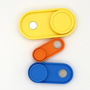 May include: Three colorful, oval-shaped fidget toys in yellow, orange, and blue. Each toy has a circular, textured slider and a small, silver magnet. The toys are arranged vertically against a white background.